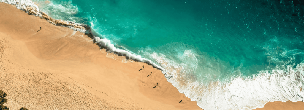 Bird's-eye view of a beautiful beach, highlighting the rhythmic waves and smooth sand, evoking a sense of calm and relaxation.