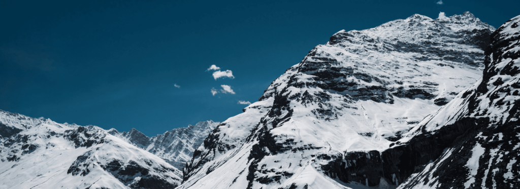A majestic mountain covered in snow stands tall under a bright blue sky, highlighting the tranquility of the landscape.
