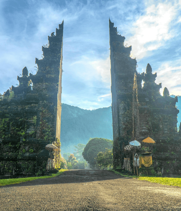 a stone gate with trees and mountains in the background
