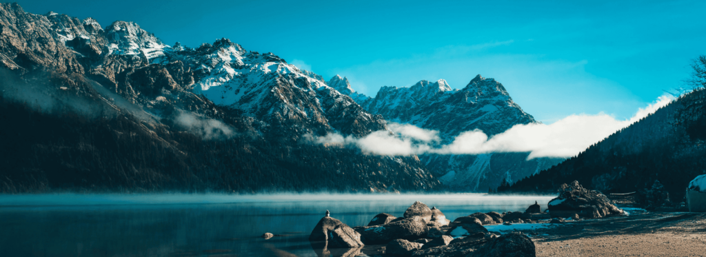 a lake with snow covered mountains and clouds