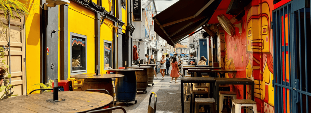 A narrow alley featuring outdoor tables and chairs, inviting patrons to enjoy their meals in a cozy atmosphere.