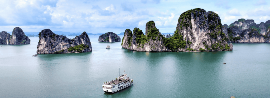 A serene view of Halong Bay in Vietnam, showcasing its iconic limestone karsts and tranquil waters under a clear sky.
