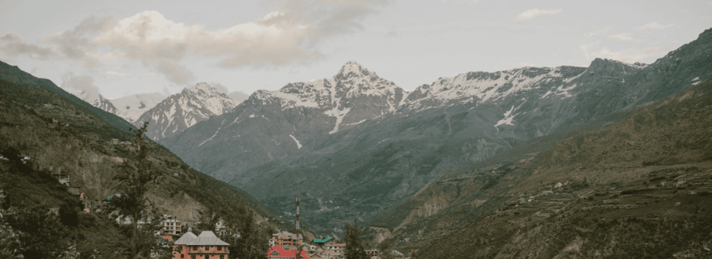A picturesque small village nestled in the mountains, framed by a stunning mountain range in the background.