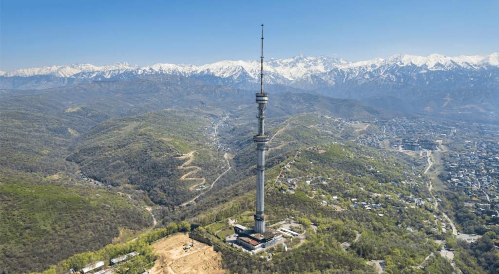 a tower in the middle of a valley with mountains in the background