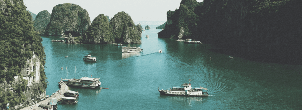 Boats gently float on the water, with a majestic mountain rising in the background, creating a serene landscape.